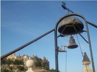 Vista de les campanes del rellotge amb el castell al fons