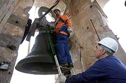 Dos operarios se preparan para retirar una de las campanas que se restaurarán