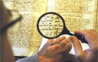 Xavier Serra observa, a través de la lupa, el manuscrito de 1527 de la 