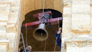 Dos operarios trabajan en el montaje de una de las campanas restauradas