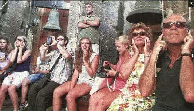 Los turistan se tapan los oídos ante el fuerte tañido de una campana